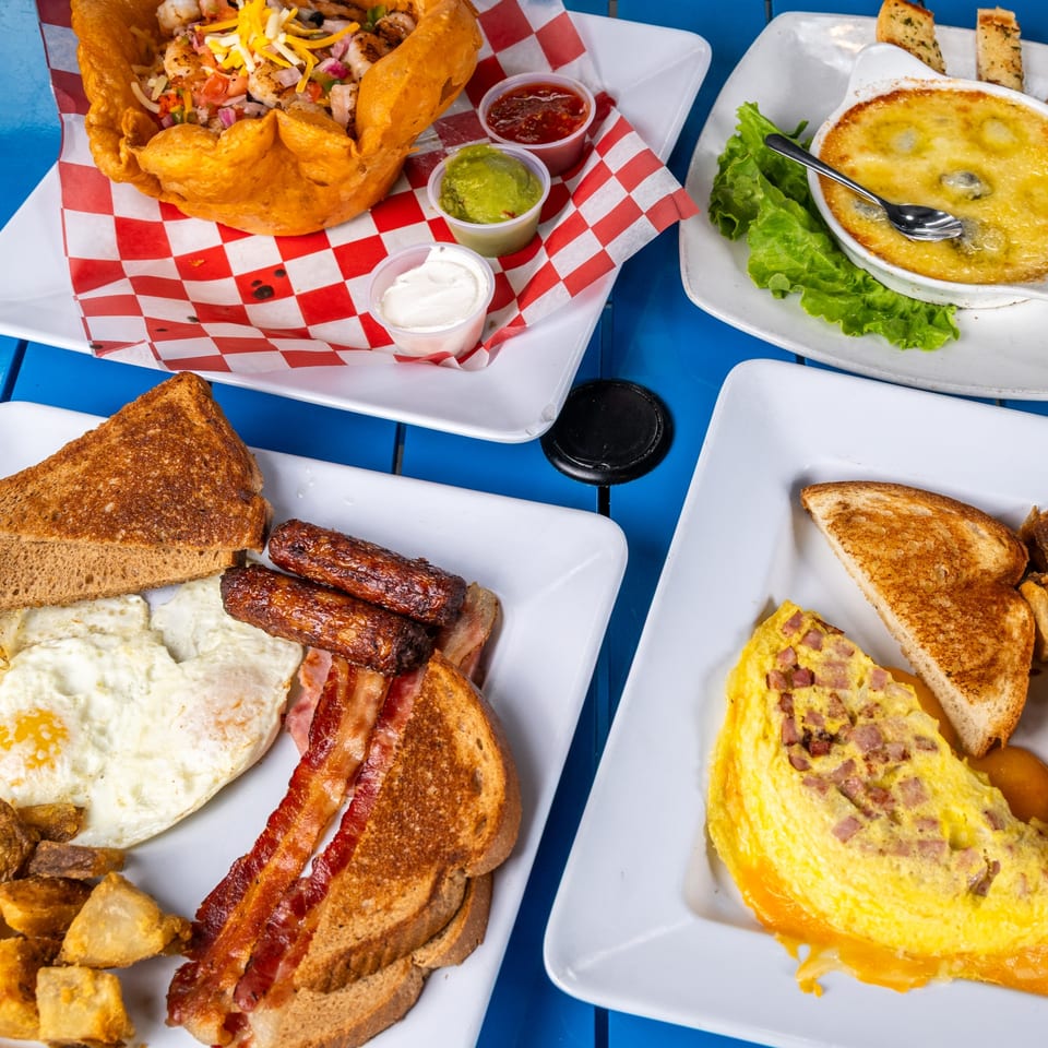 A vibrant blue table laden with a variety of breakfast and lunch dishes, including a taco salad.